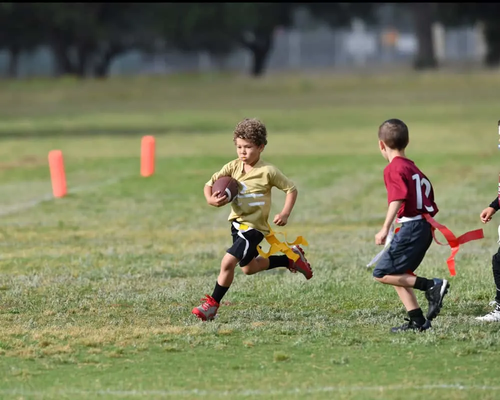 Young boy running with the ball during a youth flag football game
