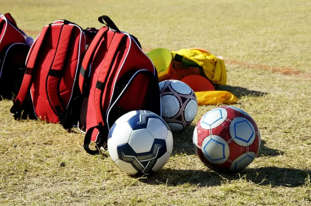 Soccer balls and bags on the sidelines
